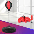 Black and red punching bag with stand and boxing gloves on a colorful floor.