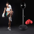 Woman in boxing pose with a punching bag and gloves on a black background