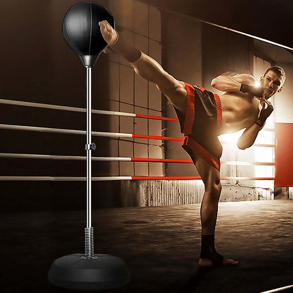 Person practicing martial arts in a boxing ring with a punching bag.