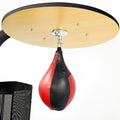 Red and black punching bag hanging from a ceiling mount on a white background
