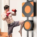 Man in boxing gloves and shorts practicing a kick on a punching bag.