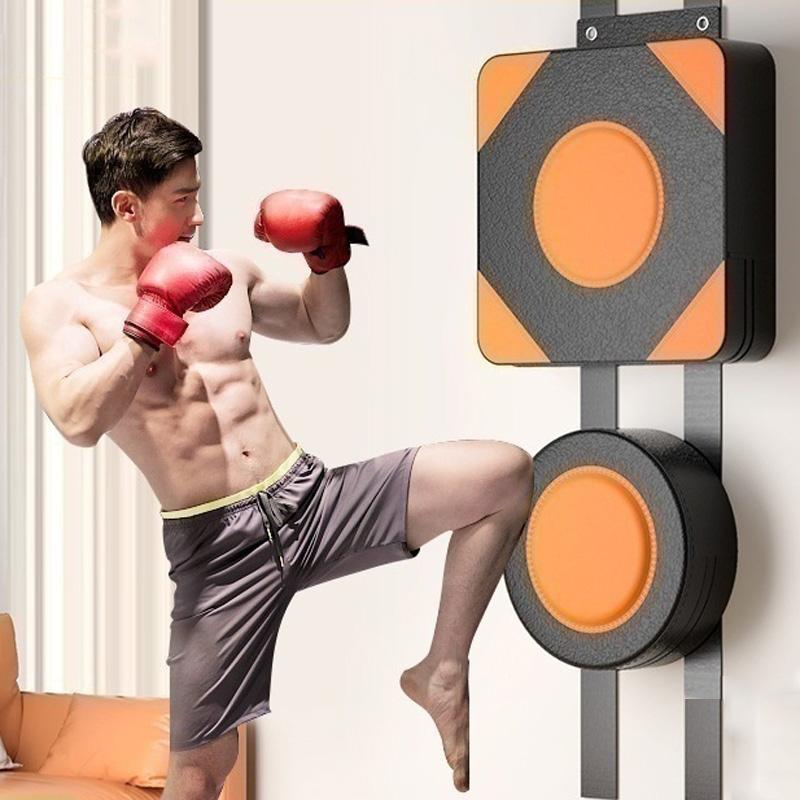 Man in boxing gloves and shorts practicing a kick on a punching bag.