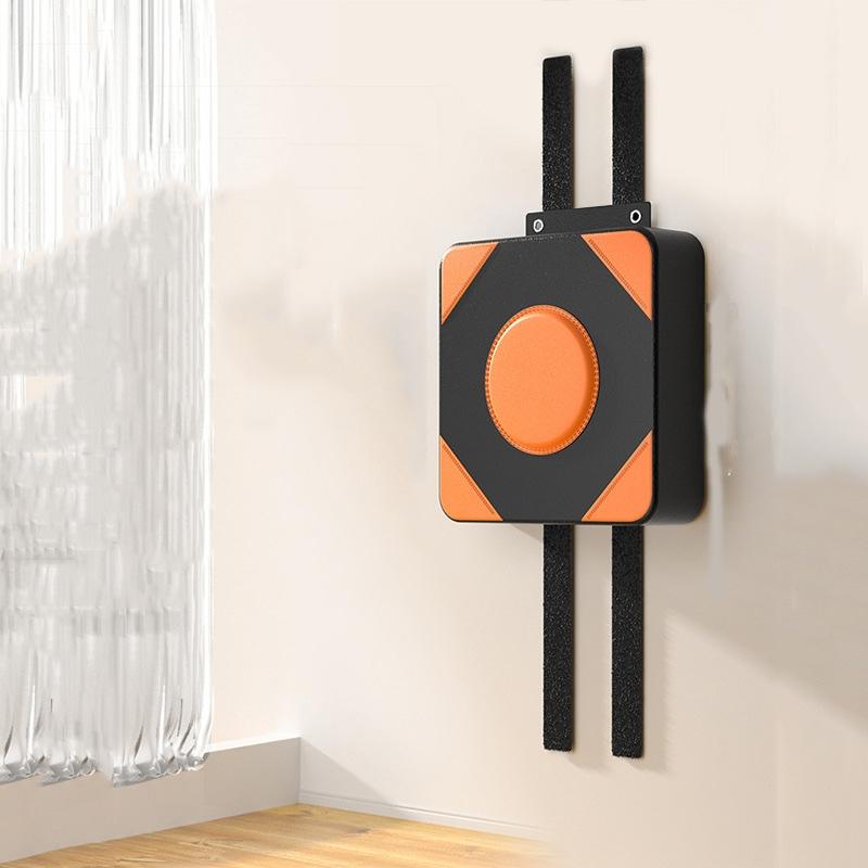 Black and orange wall-mounted device in a room with a window and wooden floor.