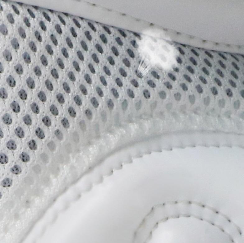 Close-up of a white sneaker with textured mesh and white sole.