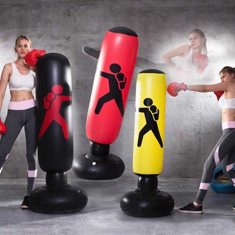 Three inflatable punching bags with a woman practicing boxing in the background.
