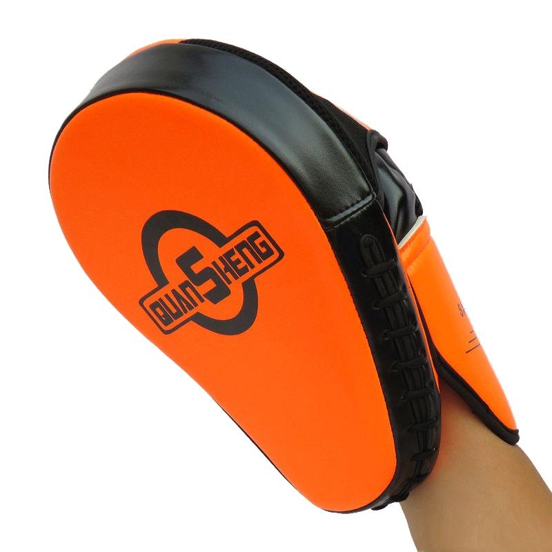 Orange and black martial arts training pad held by a hand on a white background