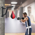 Person training with a boxing bag attached to a wall bracket in a gym.