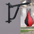 Black punching bag stand attached to a gray wall with a red and black punching bag hanging from it.