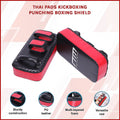 Red and black Thai pads for kickboxing with brand logo on a light pink background