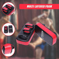 Red and black boxing training pads with 'TM' branding on a blurred background of people exercising.