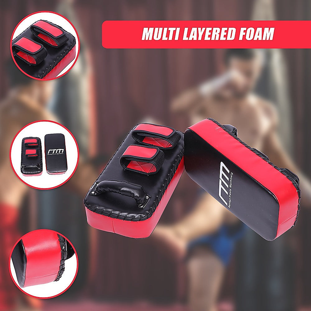 Red and black boxing training pads with 'TM' branding on a blurred background of people exercising.